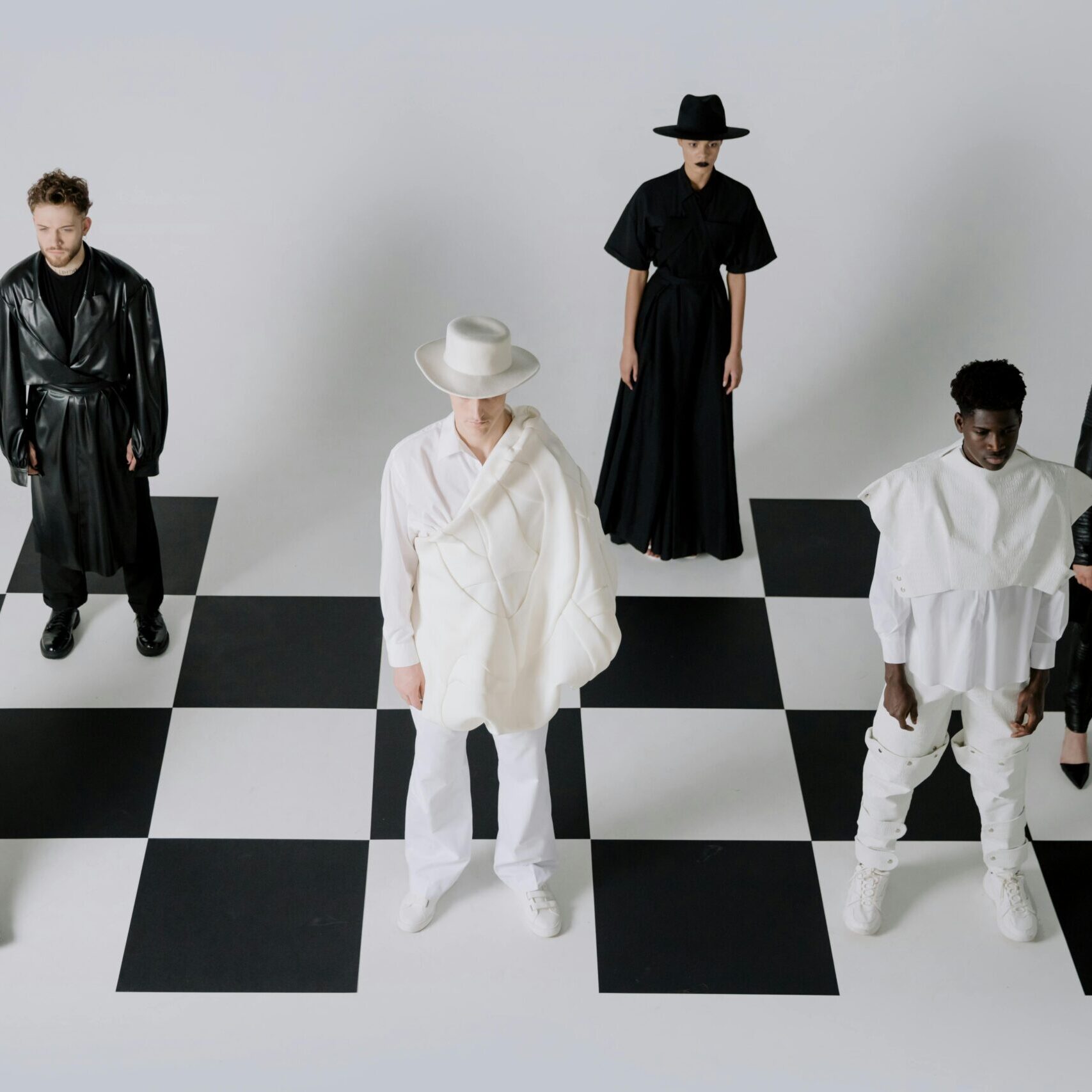 Stylish fashion models in black and white outfits on a chessboard backdrop.